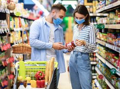 Junge Frau und junger Mann sehen sich Konserve im Supermarkt an