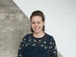 The picture shows a young woman, Helen Ahner, in portrait in front of a wall at the Max Planck Institute for Human Development in Berlin.
