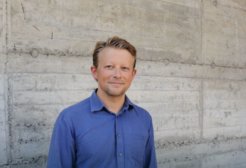 Auf dem Bild steht Philipp Lorenz-Spreen (männlich) vor einer Betonwand. Er trägt ein dunkelblaues Hemd und hat kurze, blonde Haare.
