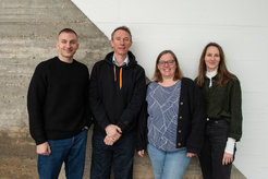 vier Personen stehen vor einer Betonwand