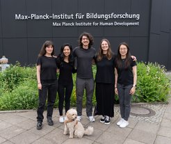 Group picture showing 5 people and a dog in front of the building of the MPIB