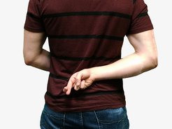 Eine Person kreuzt hinter dem Rücken die Finger