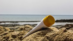 Eine Tube Sonnencreme, die im Sand in der Sonne lieg