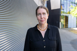 The photo shows the portrait of Simone Kühn next to a gray wall.